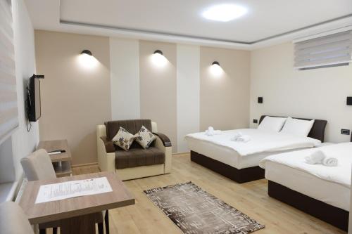a room with two beds and a chair and a table at Kovač Residence in Zrenjanin