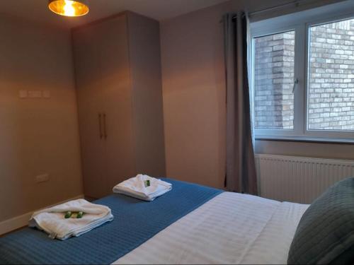 - une chambre avec 2 serviettes sur un lit et une fenêtre dans l'établissement Apartments Heathrow - Hounslow, à Cranford