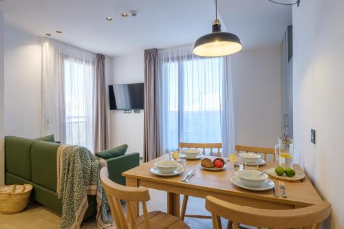 a dining room with a table and a green couch at Tgna Reial 1 in Tarragona