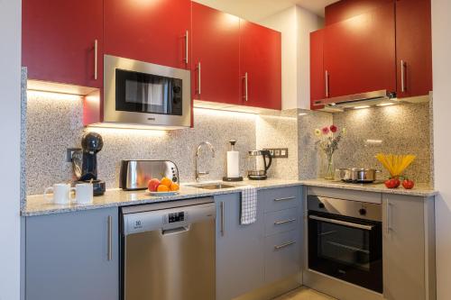 a kitchen with red cabinets and stainless steel appliances at Tgna Reial 1 in Tarragona