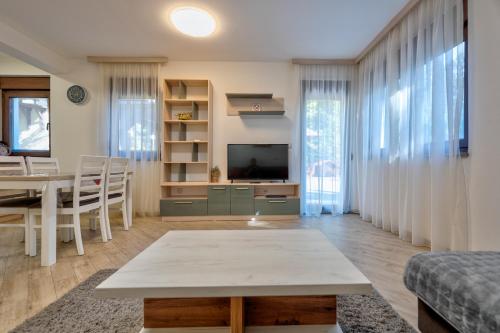 a living room with a table and a television at Lovac apartmani in Zlatibor