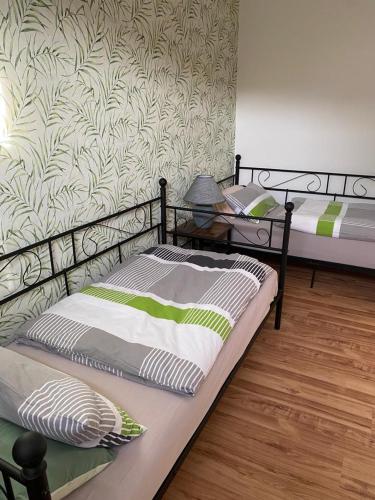 2 camas individuais num quarto com uma parede em familienfreundliche Ferienwohnung Tina em Rollshausen