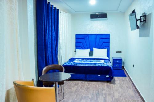 a bedroom with a blue bed and a table and chairs at HOTEL BORJ EL ARAB in Khouribga