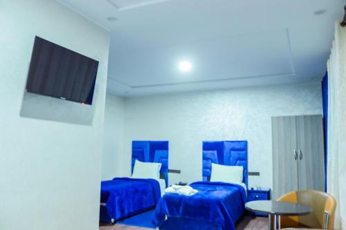 a room with two beds and a tv and a table at HOTEL BORJ EL ARAB in Khouribga