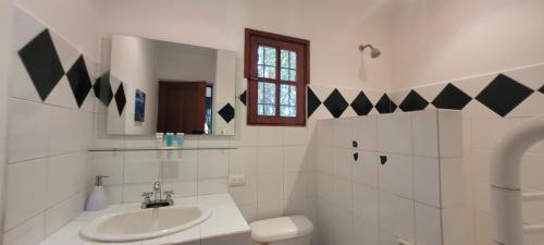 um banheiro branco com uma pia e um espelho em Cabinas Corazon em Tamarindo