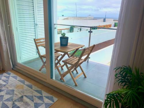 a table and chairs on a balcony with a window at L'Azor Suites - Océan in Ponta Delgada