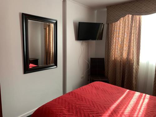 une chambre avec un lit rouge et un miroir dans l'établissement Condominio Espacio 1, à La Serena