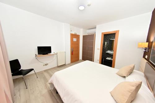 a bedroom with a white bed and a chair at Hostal Falfes in Madrid