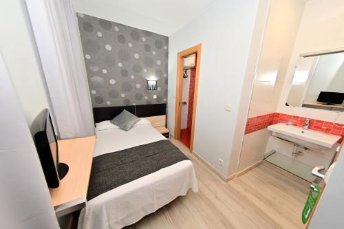 a small bedroom with a bed and a mirror at Hostal Falfes in Madrid