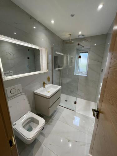 a white bathroom with a toilet and a shower at Lux Cottage in Blackburn