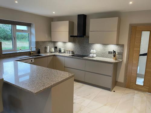 eine Küche mit weißen Schränken und Granitarbeitsflächen in der Unterkunft Lux Cottage in Blackburn