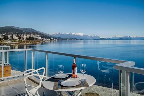 uma mesa com 2 copos de vinho numa varanda com vista para um lago em Bariloche costa del lago Ollagua em San Carlos de Bariloche