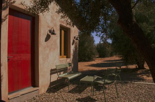 a building with a red door and a group of chairs at Alma Liebre Viñedos del Valle in Valle de Guadalupe