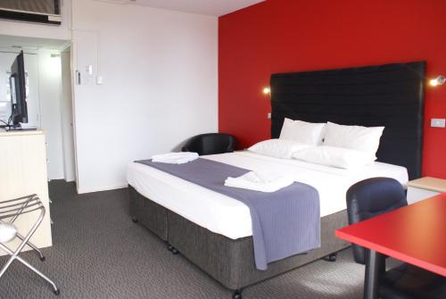 a bedroom with a large bed and a red wall at Darwin Poinciana Inn in Darwin