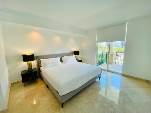 a bedroom with a white bed and a large window at The King David Condos in Miami Beach