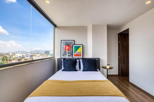 Un dormitorio con una cama y una ventana grande. en ULIV Apartments Polanco, en Ciudad de México