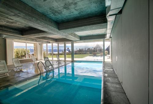 a swimming pool with chairs in a house at Bariloche costa del lago Ollagua in San Carlos de Bariloche