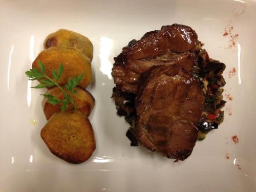 a white plate with a piece of meat and some potatoes at Terrazas Del Calafate in El Calafate