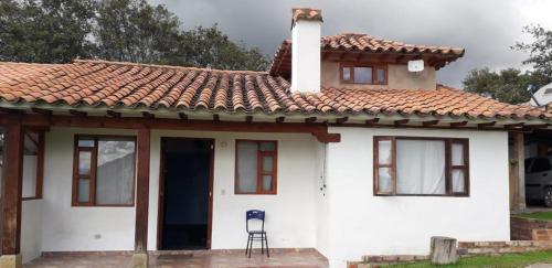 una pequeña casa blanca con una silla delante en Cabaña El Mirador M&G en La Capilla
