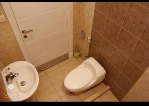 La salle de bains est pourvue de toilettes blanches et d'un lavabo. dans l'établissement Al Makan Suites 102 by Al Azmy, à Riyad