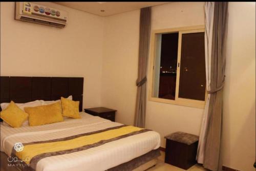 a bedroom with a bed with yellow pillows and a window at Al Makan Suites 102 by Al Azmy in Riyadh