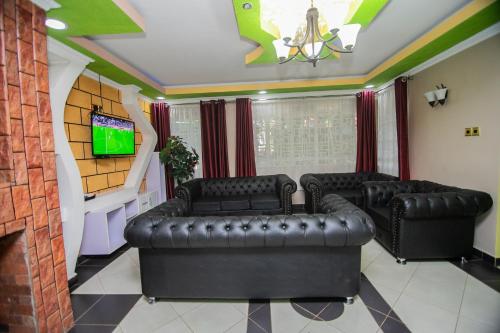 a living room with black leather couches and a tv at Lovely Garden Guest Home in Kisumu