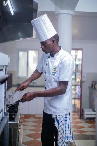 a man wearing a chefs hat standing in front of an oven at Lovely Garden Guest Home in Kisumu