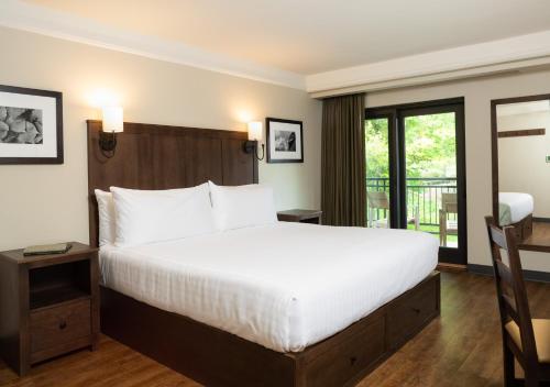 a bedroom with a large white bed and a balcony at Kanuga Inn & Lodging in Hendersonville