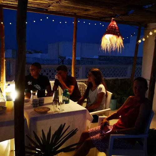 a group of people sitting at a table at night at Dar Evelyne by Daldoul in Mahdia