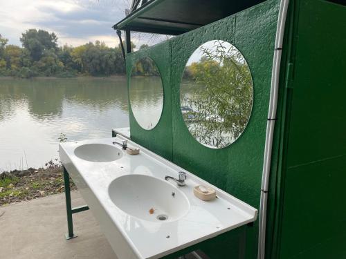 een groene badkamer met een wastafel en een spiegel bij Tisza-beach wild camping 5 in Szeged