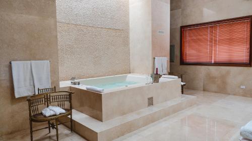 La grande salle de bains est pourvue d'une baignoire et d'une chaise. dans l'établissement Hotel & Hacienda La Caravedo, à Ica
