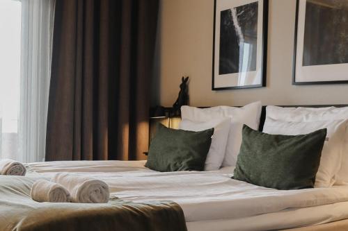 a bed with white sheets and green pillows at Siljansnäs Hotell in Siljansnäs