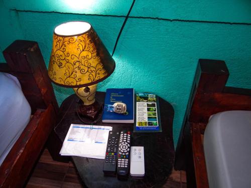 a table with a lamp and remote controls on it at Posada Río Celeste La Amistad in Rio Celeste