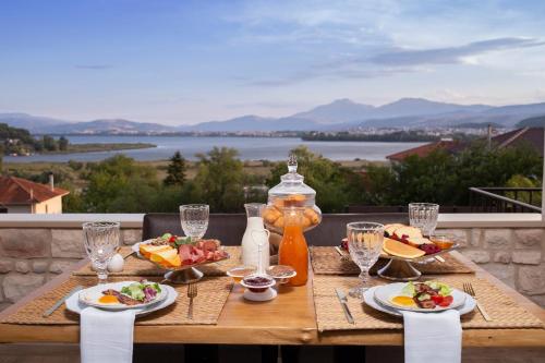 einen Holztisch mit Tellern aus Essen auf dem Balkon in der Unterkunft MONTANA LAKE VIEW in Ioannina