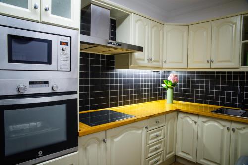 a kitchen with white cabinets and black tiles on the wall at Canary Treasure La Laguna exclusiveness prime location in La Laguna