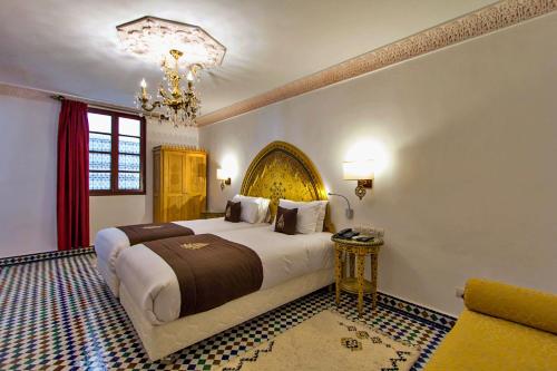 a bedroom with a large bed and a chandelier at Riad Marjana suites & Spa in Fez