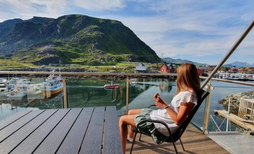 uma mulher sentada numa cadeira com vista para uma marina em Lofoten Seaside em Ballstad