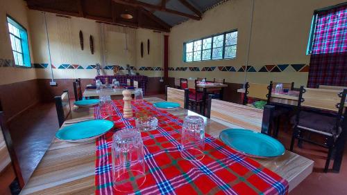 una sala da pranzo con un lungo tavolo con piatti e bicchieri di Greenwood safari camp a Talek