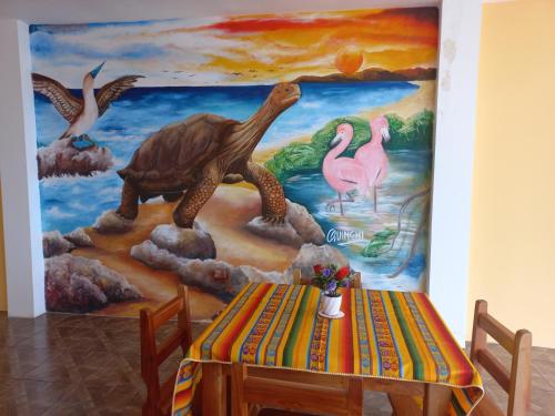 a table in front of a painting of dinosaurs at HOSTAL JANET STARLiNK in Puerto Villamil