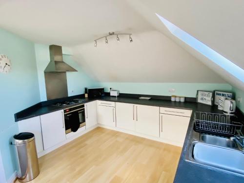 a kitchen with white cabinets and a black counter top at Swanage Holiday Penthouse Apartment, Moments from Beach and Town, On Site Parking, Fast WIFI, Sleeps up to 6, Rated Exceptional in Swanage