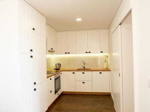 a kitchen with white cabinets and wooden floors at Casa da Portelinha in Arcos de Valdevez