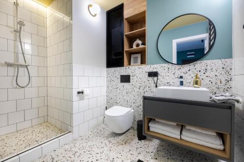 a bathroom with a sink and a toilet and a mirror at Hampton Apartments - 200 m do Plaży Apartament z balkonem i widokiem in Sopot