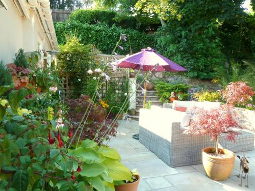 a patio with a couch and an umbrella in a garden at The Somerville in Torquay