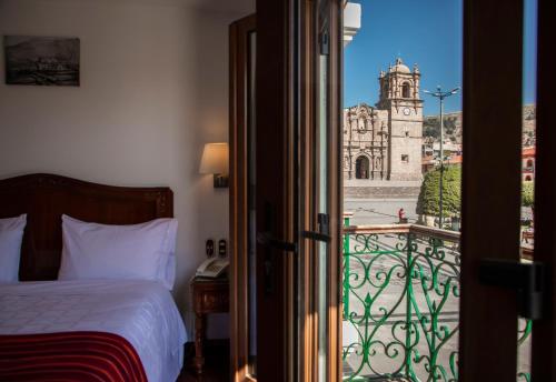 una camera con letto e vista su un edificio di Hotel Hacienda Plaza de Armas a Puno