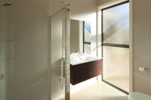 a bathroom with a sink and a glass shower at Kentmere Cottage in Lake Tekapo