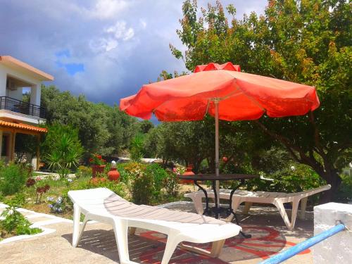 a table with a red umbrella and two chairs at Daphne Studios in Marathokampos
