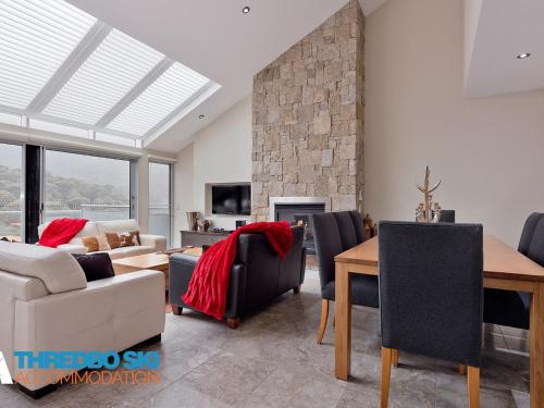 a living room with a fireplace and a table and chairs at The Peak Penthouse 9 in Thredbo