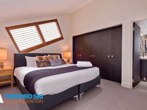 a bedroom with a large bed with a wooden headboard at The Peak Penthouse 9 in Thredbo