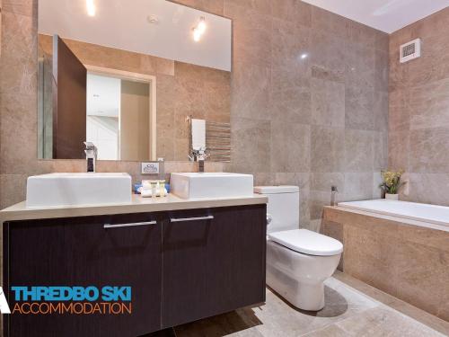 a bathroom with a sink and a toilet and a tub at The Peak Penthouse 9 in Thredbo