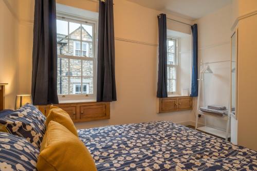 a bedroom with a bed and two windows at Kent Cottage - Town centre, with parking in Kendal